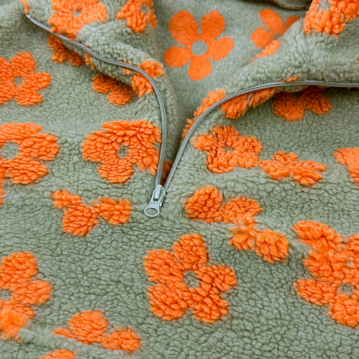 Close-up of a fabric with orange floral patterns on a green background