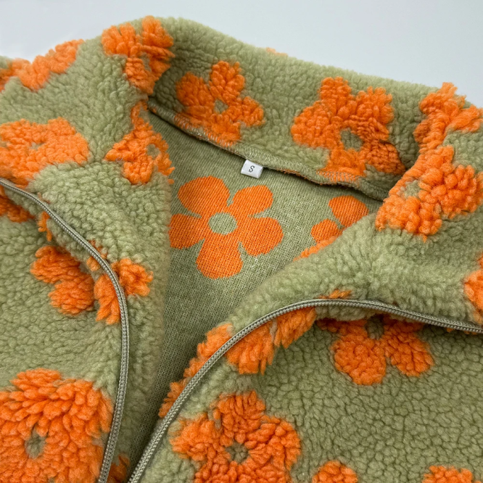 Green fleece blanket with orange floral patterns on a light gray background