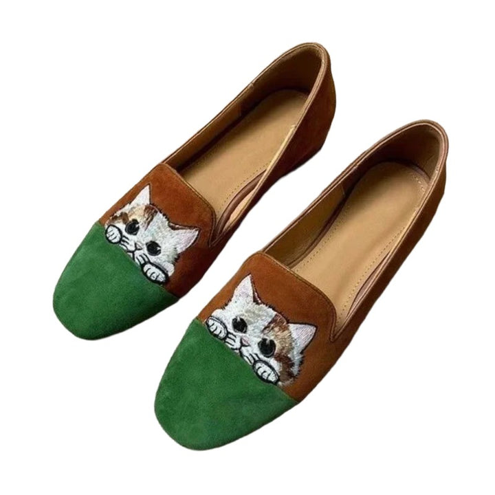Cute Cat Loafers – Brown Suede Aesthetic Shoes. A pair of slip-on loafers with a brown suede upper and a green suede toe cap, featuring a hand-painted white cat peeking out from behind the green toe area. 