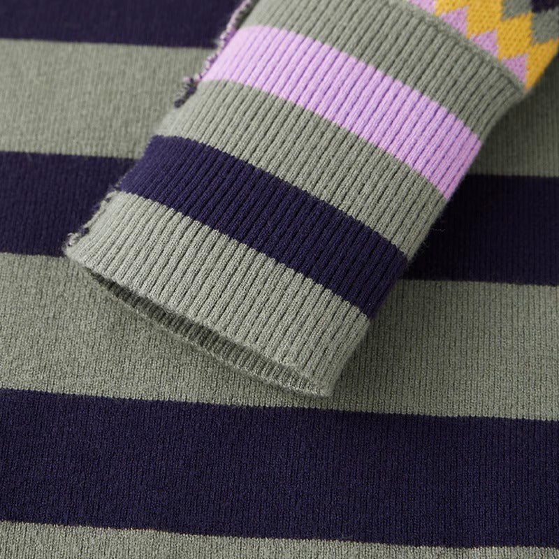 Close-up of a striped knit garment, showing a ribbed cuff with horizontal bands of olive green, lavender purple, and dark navy, with a small yellow patterned section visible at the top edge.