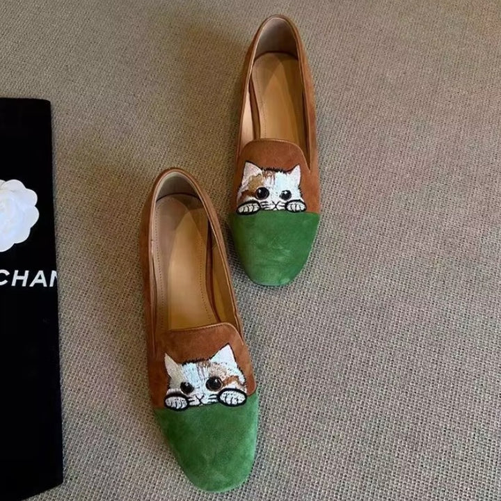 Cute Cat Loafers – Brown Suede Aesthetic Shoes. A pair of women's slip-on flats with a brown suede upper and a green suede toe cap, featuring a hand-painted tabby cat face on the vamp. 