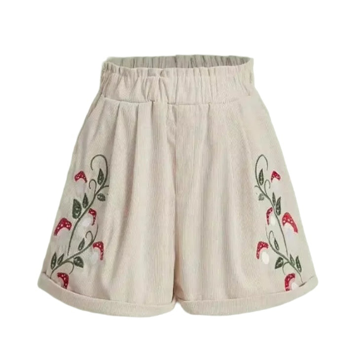 Cottagecore Mushroom Shorts – Cottagecore Aesthetic Clothing. A pair of high-waisted, wide-leg shorts in a textured cream corduroy fabric, featuring embroidered floral vine patterns with red flowers and green leaves on both sides.